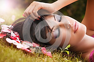 Beauty portrait of woman with flower petals near face