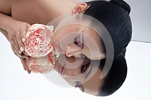 Beauty portrait of a woman lying on the floor, pink makeup and flowers, clean skin, natural cosmetics, spa treatments