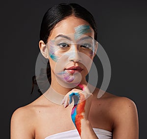 Beauty, portrait and woman with paint art on hand and face in studio. Creative skin and rainbow makeup on serious female