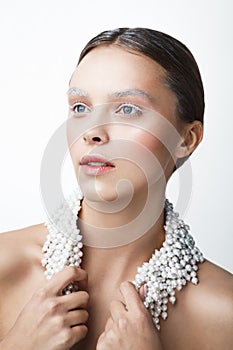 Beauty portrait of woman with pearl necklace. White and cold make-up