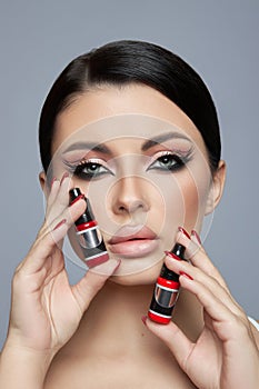 Beauty portrait of a woman, pink eye shadow makeup, arrows and long eyelashes. Brunette woman, red nail polish, natural cosmetics