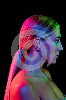 Beauty portrait of young adorable woman with well-kept skin isolated over dark background in pink neon light. Concept of