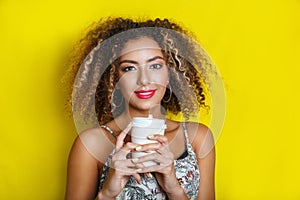 Beauty portrait of young african american girl with afro hairstyle. Girl posing on yellow background, looking at camera.