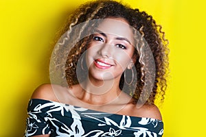 Beauty portrait of young african american girl with afro hairstyle. Girl posing on yellow background, looking at camera.