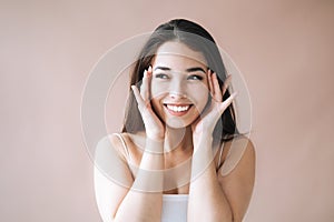 Beauty portrait of young asian woman with healthy dark long hair in top on beige background