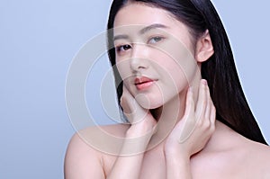 Beauty portrait of a young beautiful woman with hand on her neck shoulder isolated on gray background looking at camera, concept