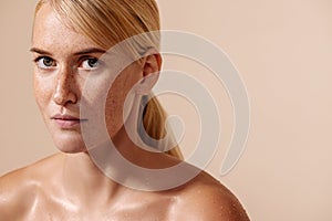 Beauty portrait of a young blond woman. Female with freckles looking straight of a camera