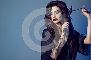 Beauty portrait of young gorgeous model in black silk peignoir with long hair and provocative make-up trying to curl her hair