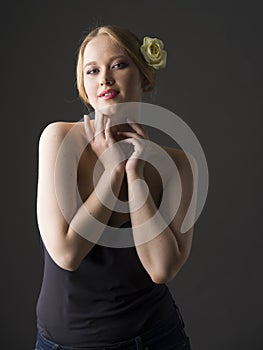 Beauty portrait of a young plus size blonde with yellow rose in her hair