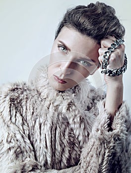 Beauty portrait of a young white woman in fur with chain, look strict to camera