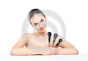 Beauty portrait of a young woman holding makeup brushes