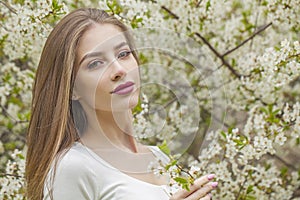 Beauty portrait of young woman with natural makeup and healthy long brown hair in blossom park outdoors. Natural female beauty