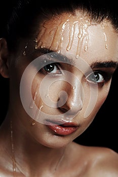 Beauty Portrait of Young Woman with Strobing Makeup Liquid on Fa
