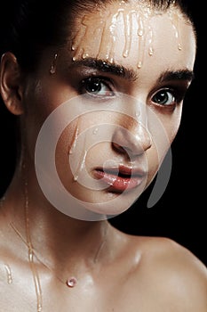 Beauty Portrait of Young Woman with Strobing Makeup Liquid on Fa