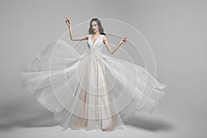 Beauty portrait of a young woman in wedding fashion long dress in waving flying fabric, cloth fluttering in wind. photo