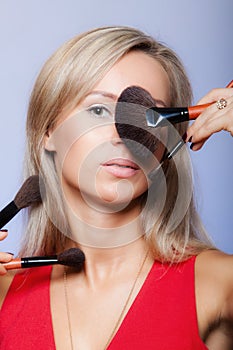 Beauty procedures, woman holds make-up brushes near face.