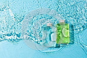 Beauty product bottles in water with copy space background on blue background