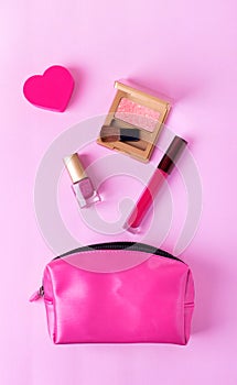 Beauty products flying out of the make-up bag on pink