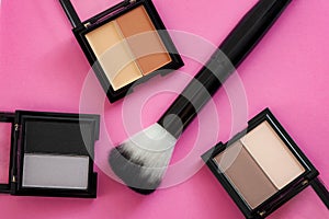Beauty products, makeup artist and face care concept with makeup brush and highlighter or bronzer powder isolated on pink
