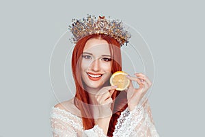 Beauty queen and Vitamin C. A young woman holding slice of orange smiling pretty woman with crystal crown on head isolated on