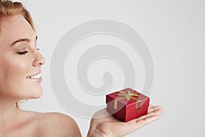 Beauty redhead woman holding hand red gift box over white empty background.