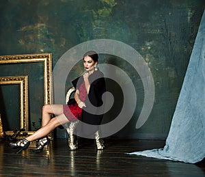 beauty rich brunette woman in luxury interior near empty frames, wearing fashion clothes, lifestyle people concept