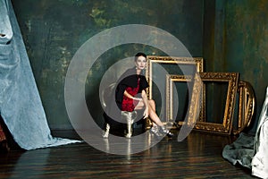 Beauty rich brunette woman in luxury interior near empty golden frames, lifestyle people concept