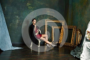 Beauty rich brunette woman in luxury interior near empty golden frames, lifestyle people concept