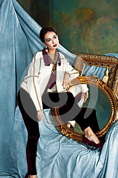 Beauty rich brunette woman in luxury interior near empty golden frames, lifestyle people concept