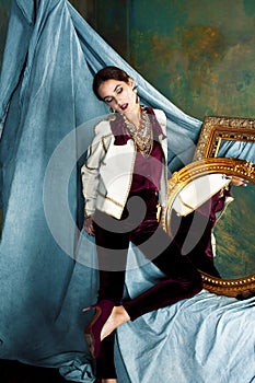 Beauty rich brunette woman in luxury interior near empty golden frames, lifestyle people concept