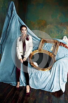 Beauty rich brunette woman in luxury interior near empty golden frames, lifestyle people concept