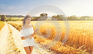 Beauty romantic girl enjoying nature in outdoors. Happy young woman in white shorts holding the ears of golden wheat