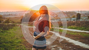 Beauty Romantic is pregnant Girl Outdoors enjoying nature holding her belly Beautiful autumn model in nature in the rays of sunset