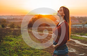 Beauty Romantic is pregnant Girl Outdoors enjoying nature holding her belly Beautiful autumn model in nature in the rays of sunset