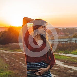 Beauty Romantic is pregnant Girl Outdoors enjoying nature holding her belly Beautiful autumn model in nature in the rays of sunset