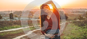 Beauty Romantic is pregnant Girl Outdoors enjoying nature holding her belly Beautiful autumn model in nature in the rays of sunset