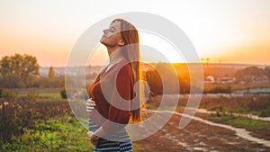 Beauty Romantic is pregnant Girl Outdoors enjoying nature holding her belly Beautiful autumn model in nature in the rays of sunset