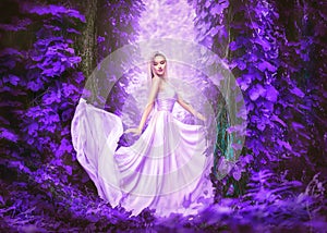 Beauty romantic young woman in long chiffon dress with gown posing in fantasy misty forest. Beautiful happy bride model girl