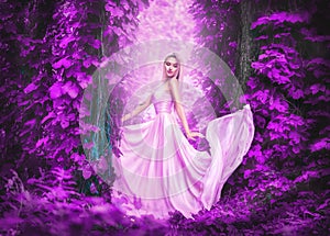 Beauty romantic young woman in long chiffon dress with gown posing in fantasy misty forest. Beautiful happy bride model girl