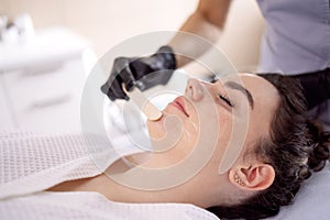 Beauty salon beautician applies cooling gel to clients skin photo