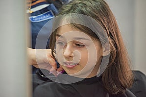 Beauty Salon Concept. Little girl cut bangs at the hairdresser. Hair cutting. 9 years old girl in a beauty salon