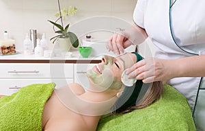 Beauty salon. Cosmetician removing facial mask from woman face.