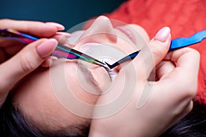 Beauty salon, eyelash extension procedure close up. Beautiful woman with long hair