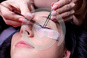 Beauty salon, eyelash extension procedure close up. Beautiful woman with long hair