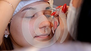 In the beauty salon the make-up artist paints eyebrows to the client