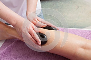 Beauty salon. Woman getting spa hot stone legs massage