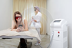 At beauty salon, woman relaxes during laser hair removal session on her legs