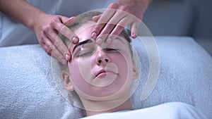 Beauty salon worker removing stencil to look at result of eyebrow coloring