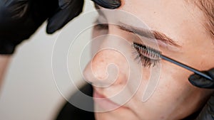 Beauty saloon. close-up, hands of the cosmetician in black rubber gloves keep a special brush and comb eyebrows. Master