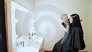 beauty saloon. the cosmetician in black rubber gloves hold tweezers and pull out eyebrows. Master corrects the shape of